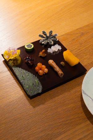 An artistic platter of garnishes and ingredients arranged on a dark serving board.