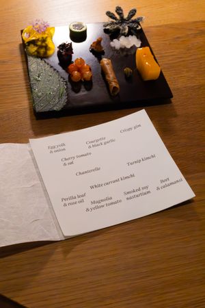 Menu labels and small plated dishes displayed on dark slate boards with colorful garnishes.