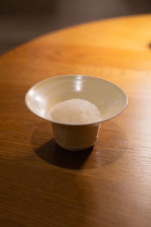 White ceramic bowl with curved edges photographed on wooden table surface.