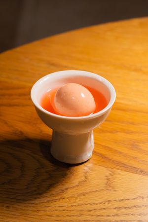 White ceramic bowl with curved edges photographed in warm lighting on wooden surface.