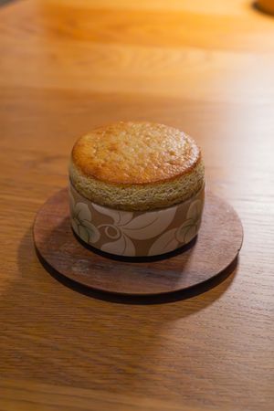 Round baked dessert served on decorative wooden plate against warm wooden table surface.
