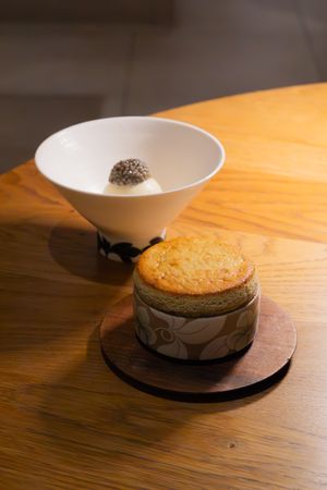 White ceramic bowl placed on dark wooden serving plate with elegant presentation.