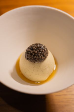 Elegant white dish with caviar garnish served in a fine dining presentation.
