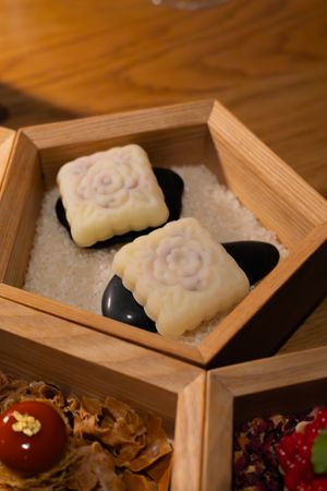 White molded desserts with floral patterns nestled in a wooden hexagonal box.