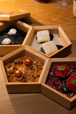 Hexagonal wooden serving boxes arranged with various garnishes and ingredients for an upscale dining presentation.