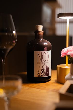 Glass bottles with custom labels illuminated by warm candlelight on a wooden table.