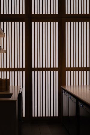 Minimalist interior architecture featuring vertical wooden slats creating geometric light patterns.
