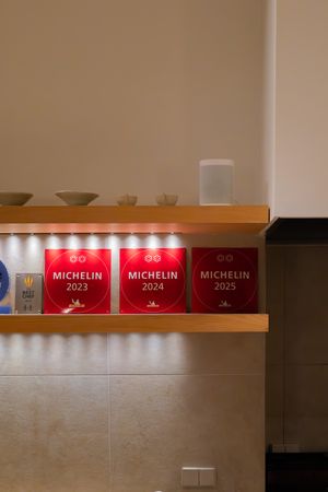 Red Michelin awards line a modern restaurant shelf displaying multiple prestigious culinary accolades earned in 2023.