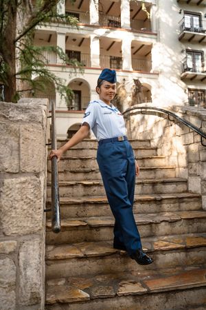 U.S. Air Force Airman in blue service uniform posing on historic stone steps near downtown San Antonio after basic training graduation.