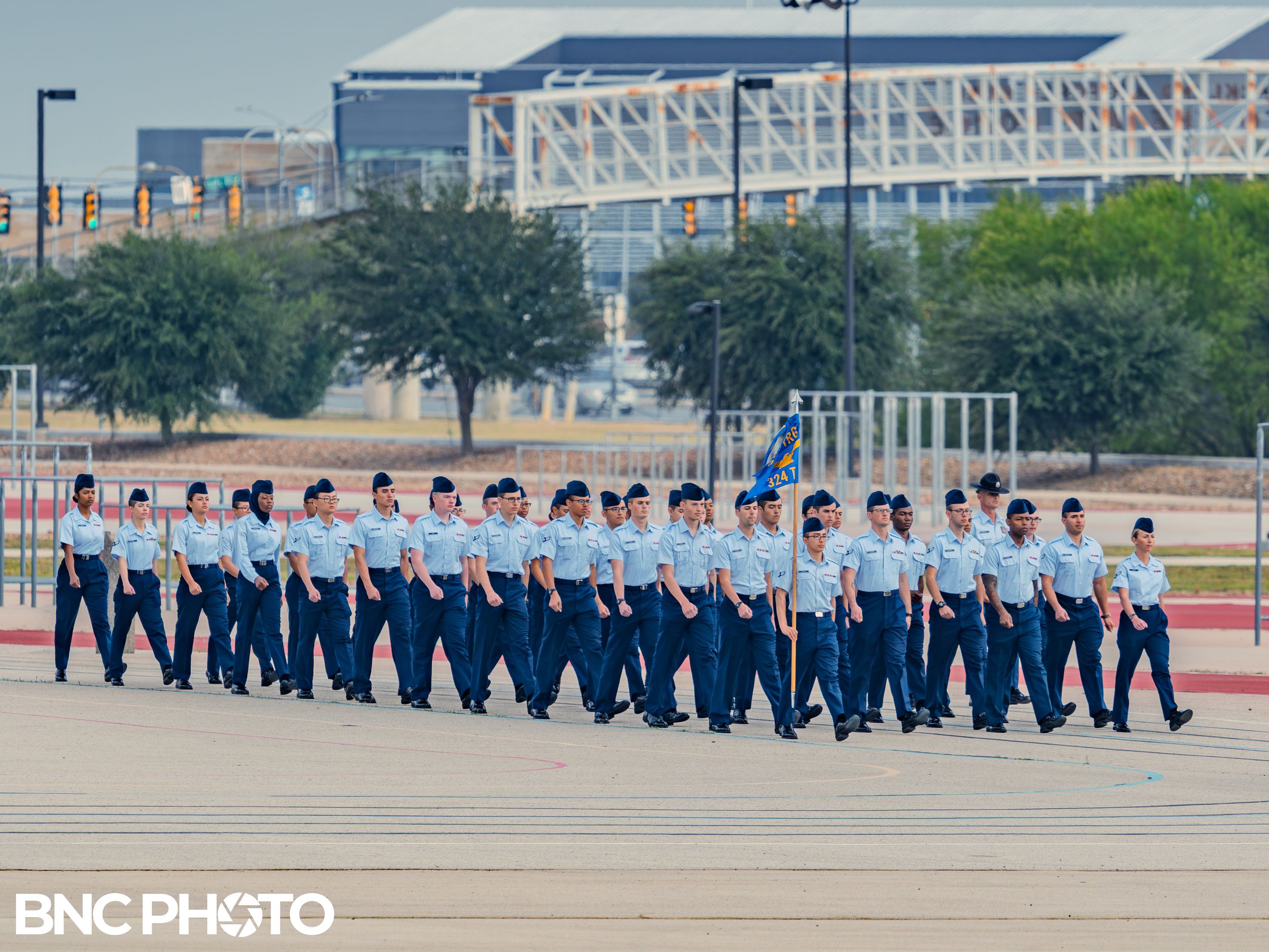 Large group of U.S. Air Force trainees marching in formation in light blue shirts and dark blue trousers at Lackland AFB.