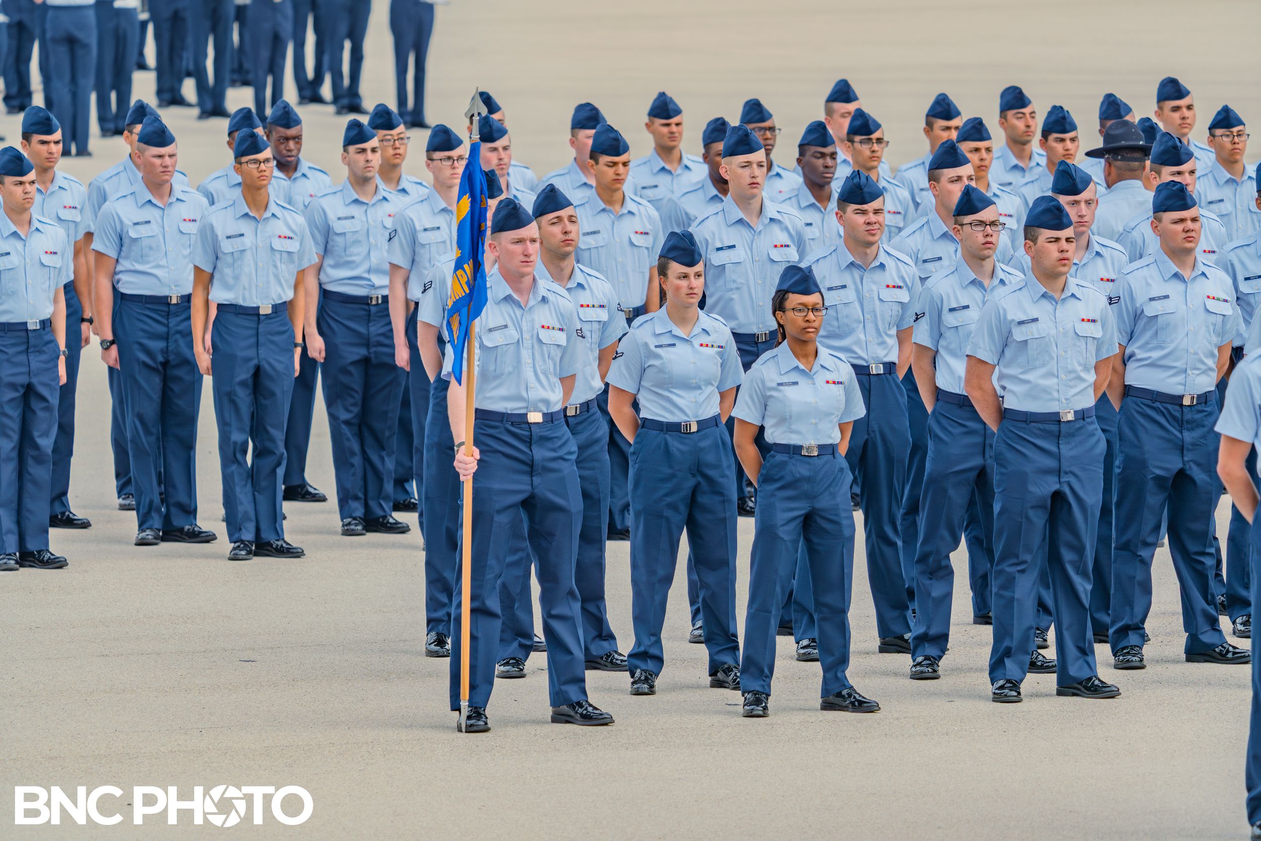 Air Force flight formation standing at attention with guidon flag on parade field at Lackland AFB.