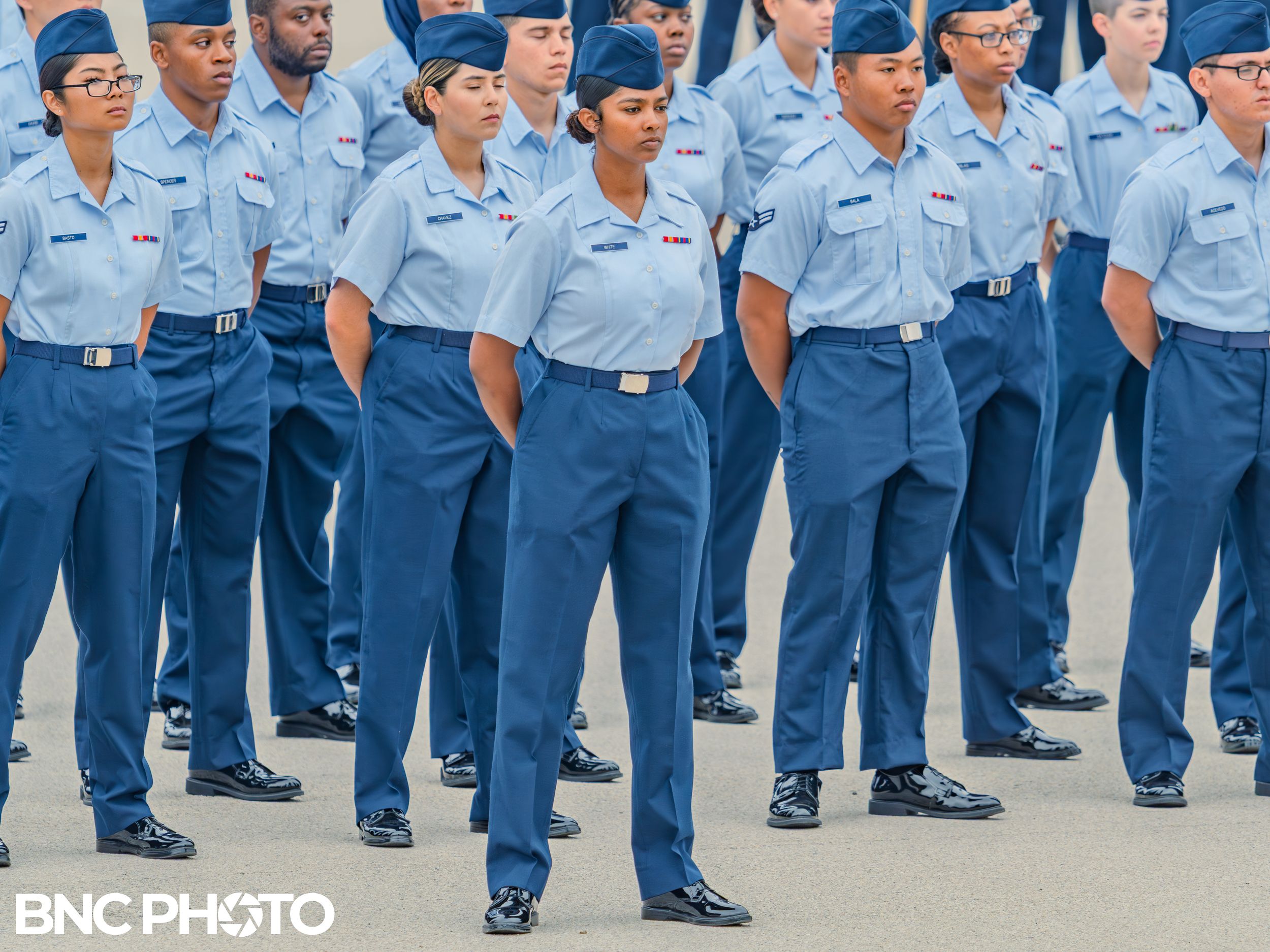 U.S. Air Force trainees in light blue shirts and dark blue trousers standing at attention during a basic military training graduation at Lac
