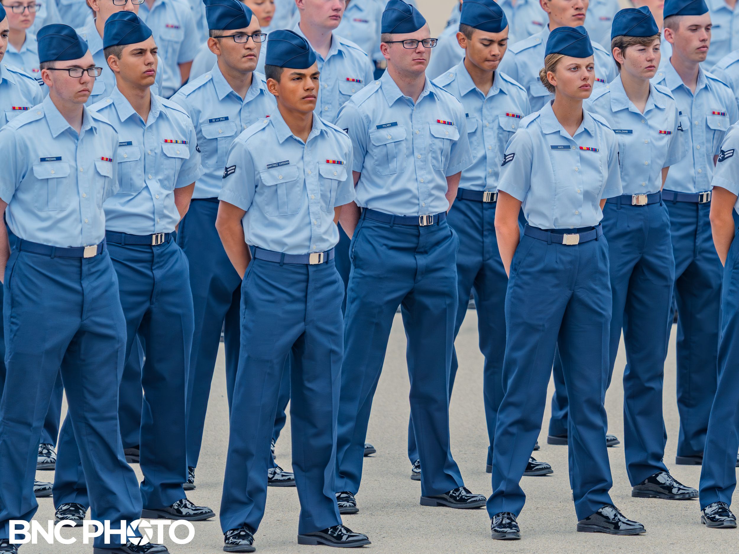 Close-up of U.S. Air Force trainees lined up in formation wearing light blue shirts and dark blue trousers during a graduation ceremony.