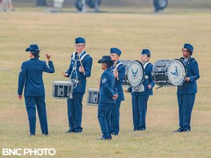 Air Force band drummers in dark blue uniforms preparing to perform on the parade field during graduation at Lackland AFB.