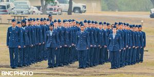 Group of U.S. Air Force graduates in blue dress uniforms standing in formation on the parade field at a military graduation.