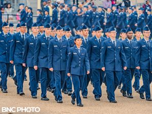 Group of U.S. Air Force graduates marching in formation on the parade field during the graduation ceremony.