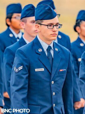 Portrait of a U.S. Air Force graduate in blue dress uniform standing at attention during the military graduation ceremony.