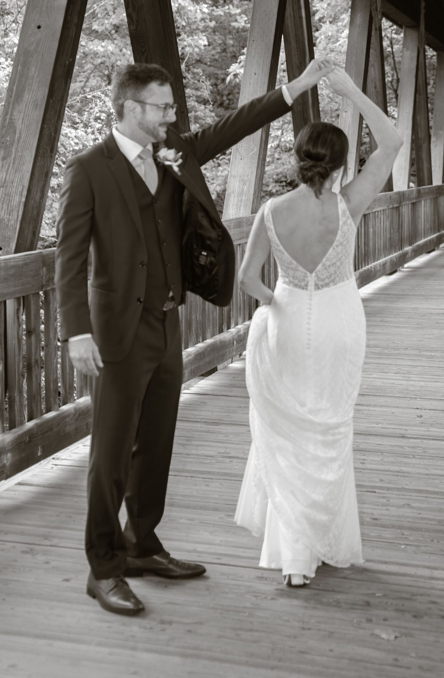 A bride and groom sharing a romantic moment in black and white photography on a covered wooden bridge.