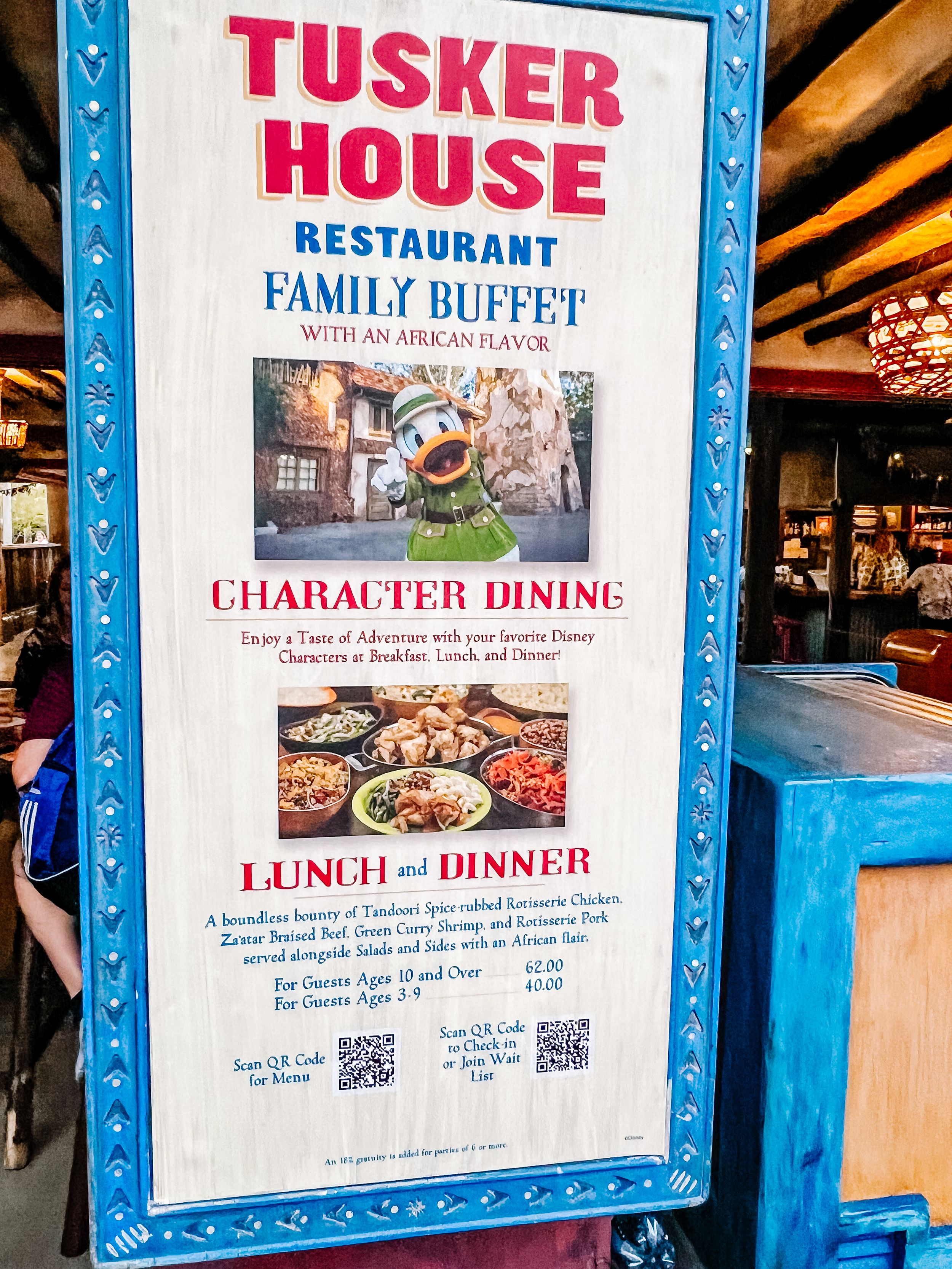 Row of framed blue and white Tusker House restaurant signs displaying dining information.