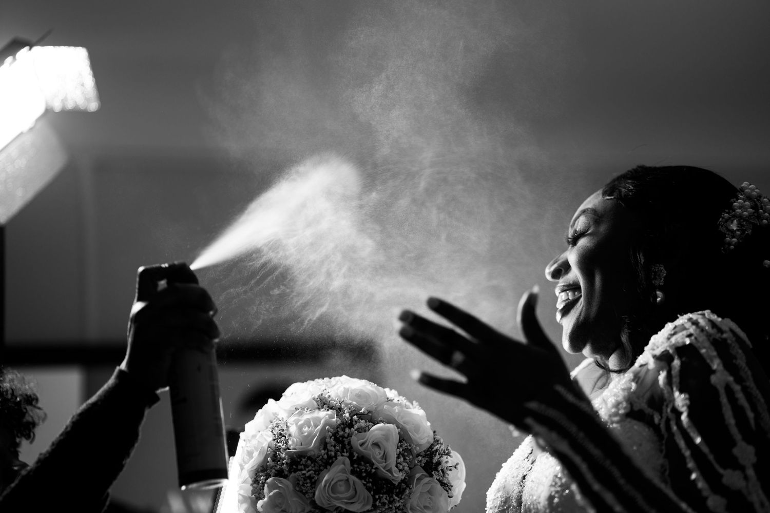 A black and white photo capturing hairspray being applied during wedding preparations.