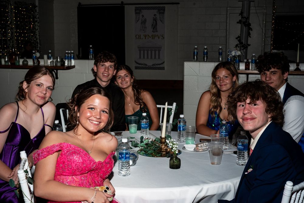 Guests seated at decorated tables during a formal event with centerpieces and drinks.