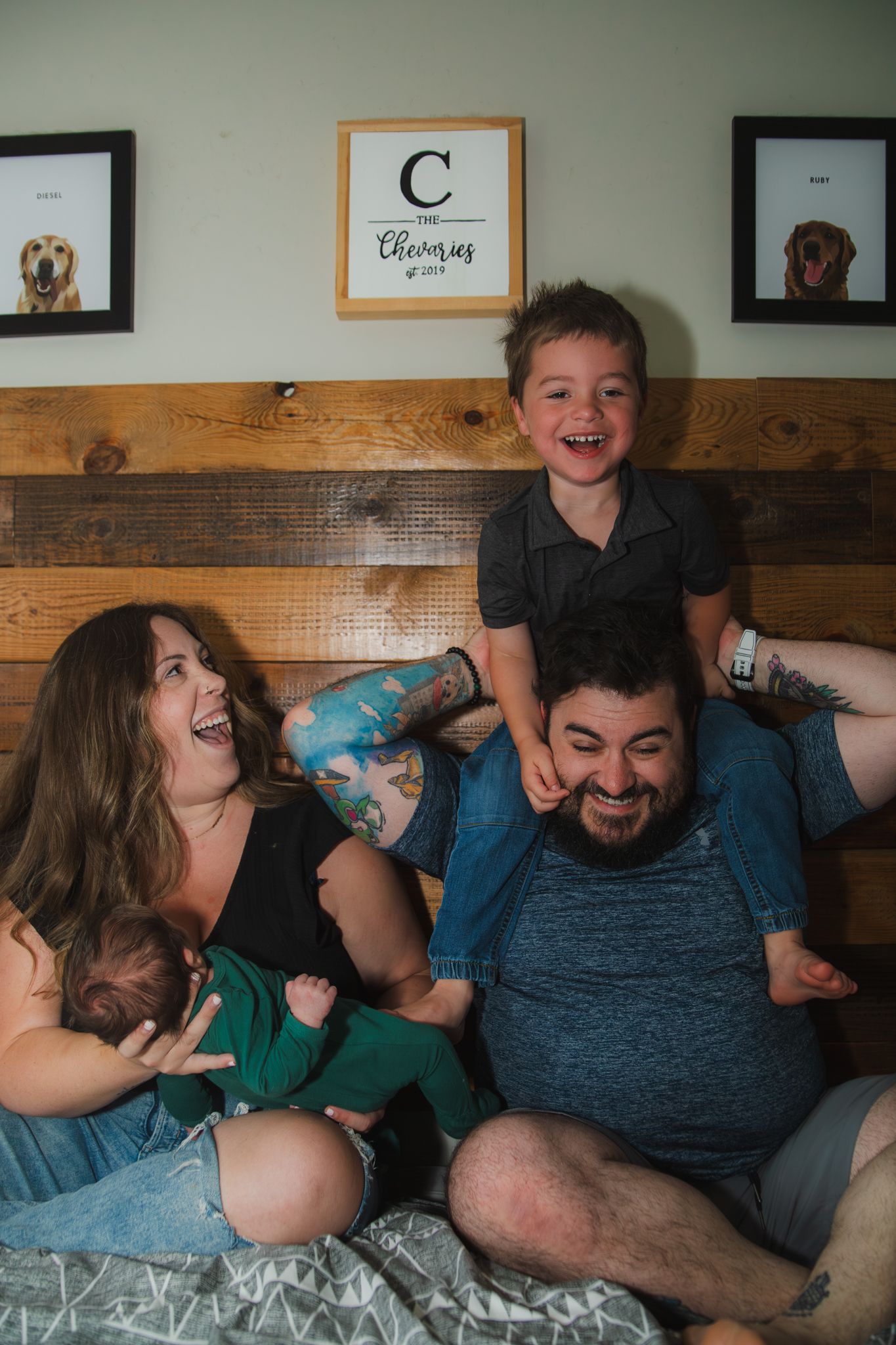 Candid family moment showing joyful laughter and playfulness on a couch decorated with framed art on the wall.