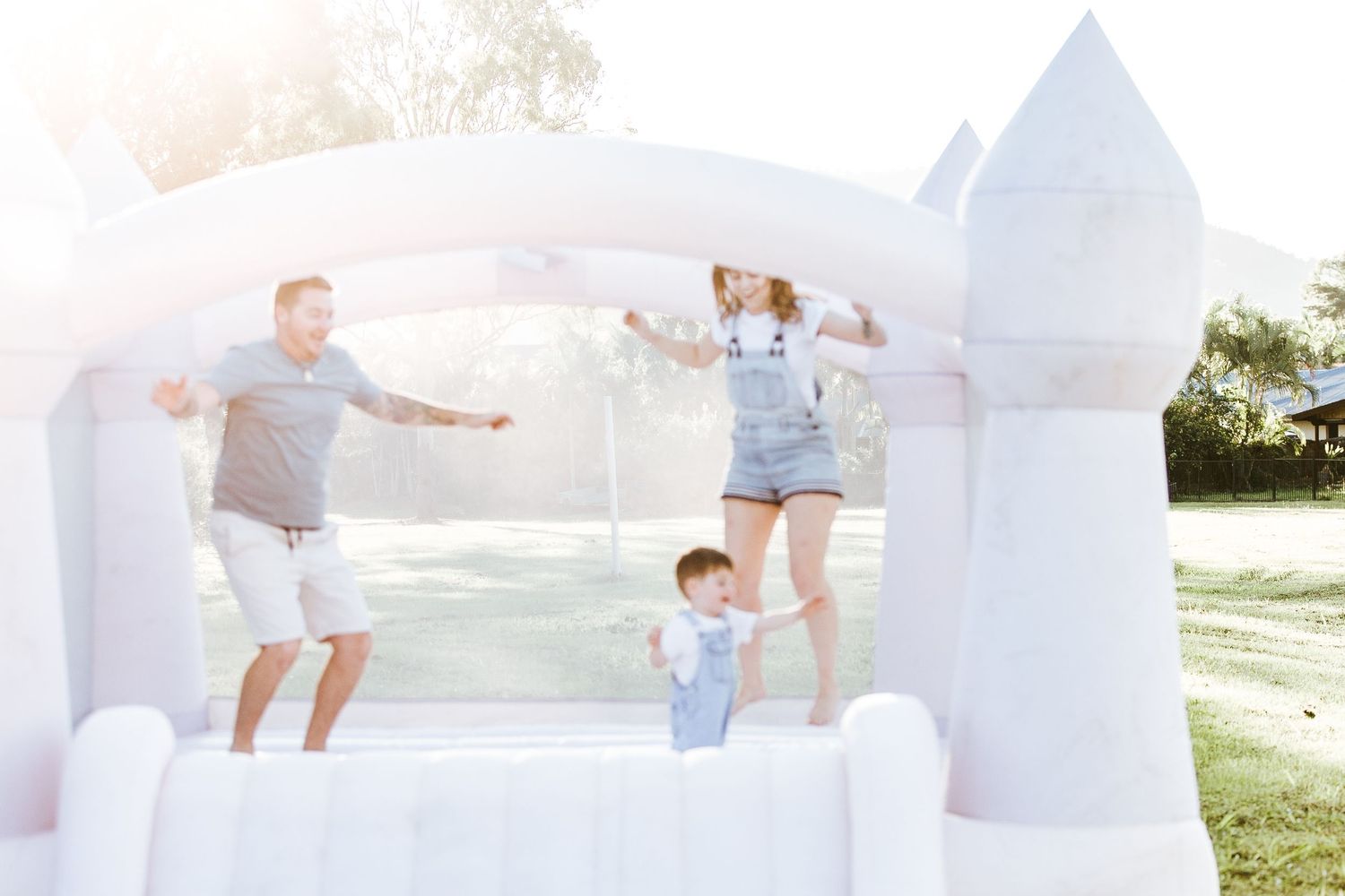 People jumping and playing together on a white inflatable bounce castle outdoors.