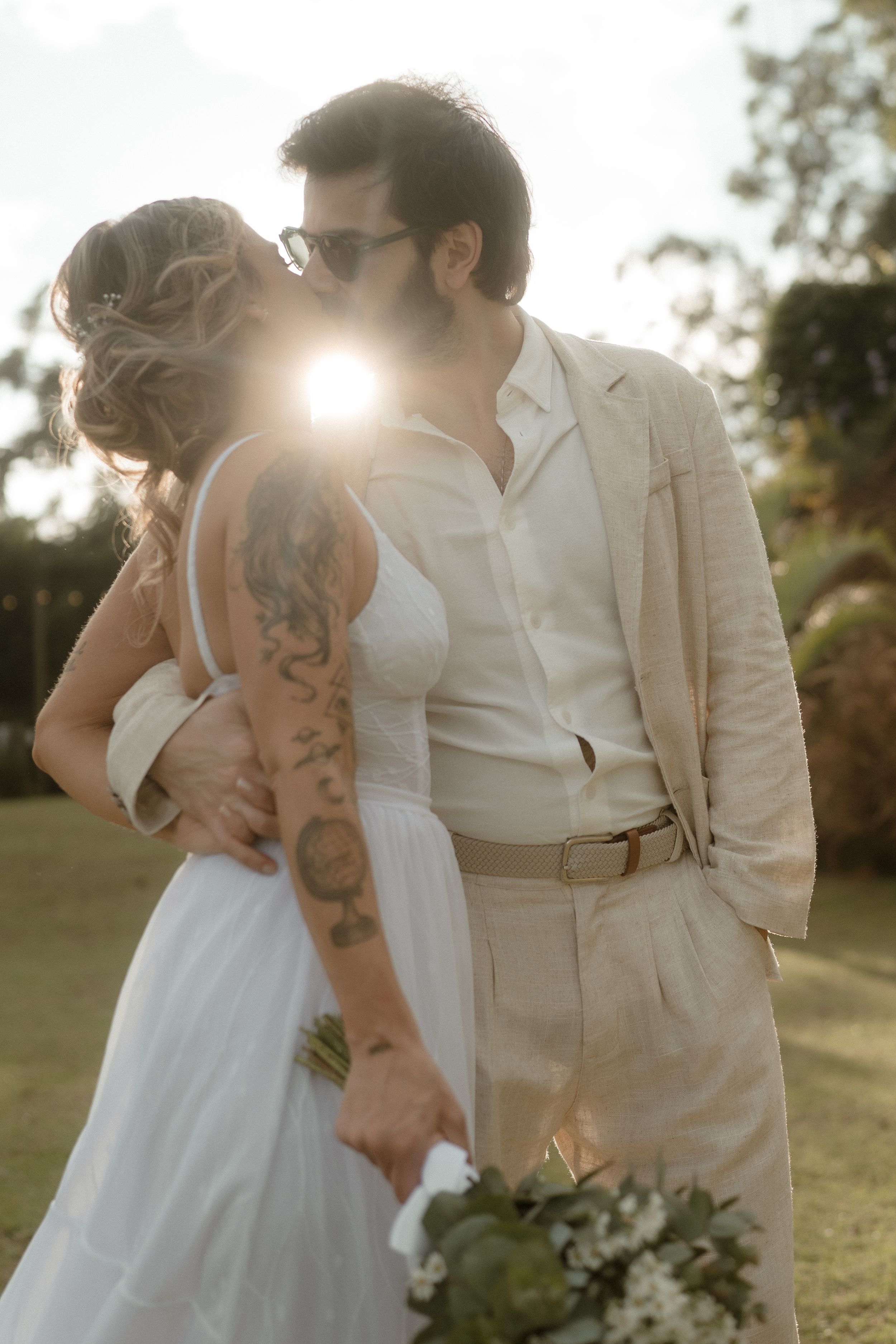 Romantic sunset wedding portrait with sunflare and natural outdoor setting.