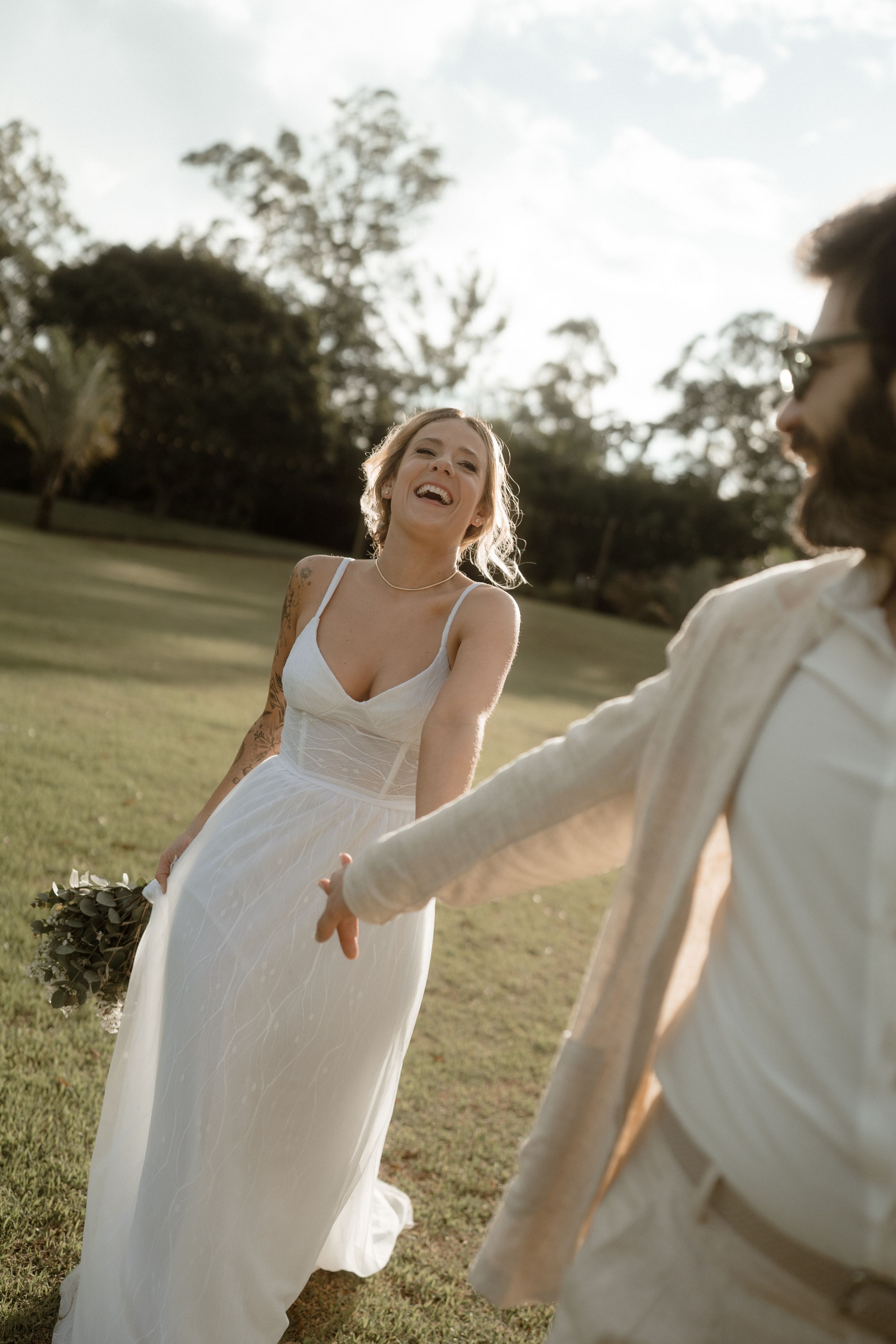 Candid moment between newlyweds laughing together in an outdoor garden setting.