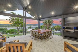 Outdoor entertainment area with dining set and BBQ featuring panoramic sunset views.