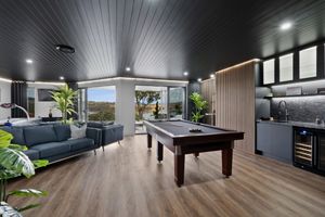 Modern living space with pool table, lounge area and entertainment setup.