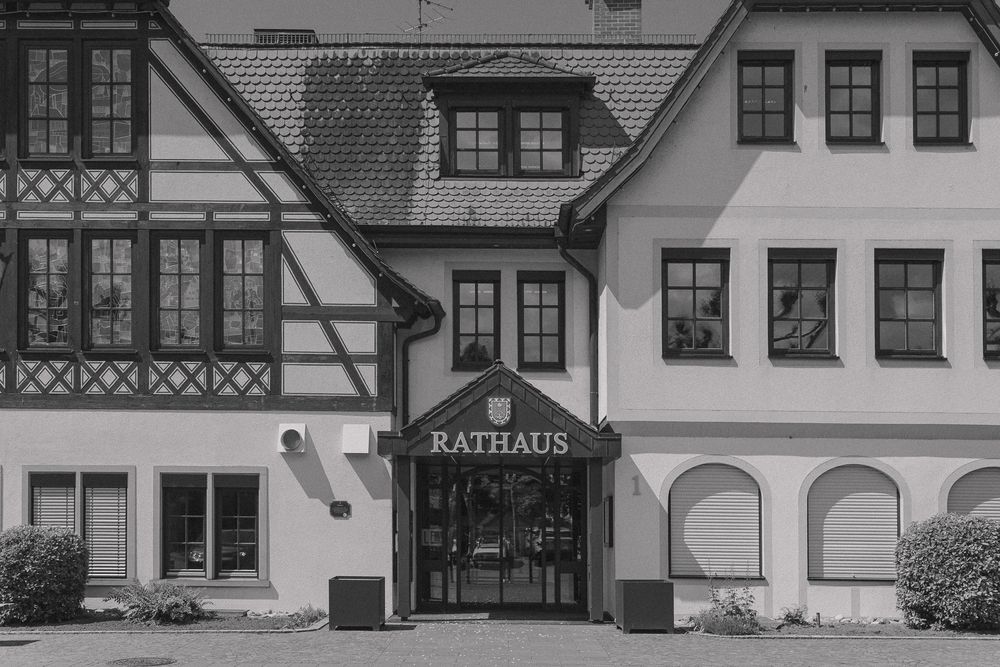 Black and white photograph of a traditional German Rathaus building entrance with half-timbered architecture and arched doorway.