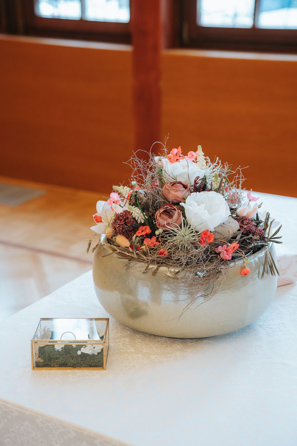 Elegant floral centerpiece arrangement with pink and white flowers in a grey ceramic bowl on white tablecloth.