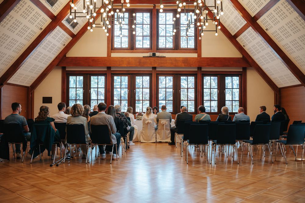 Interior of a grand wooden hall with vaulted ceiling set up for a wedding ceremony with rows of chairs.