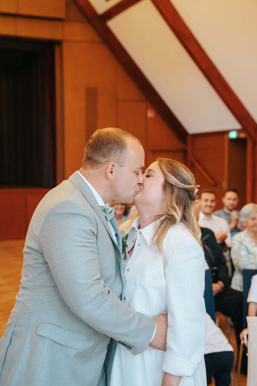 A couple shares their first kiss as newlyweds during an indoor wedding ceremony.