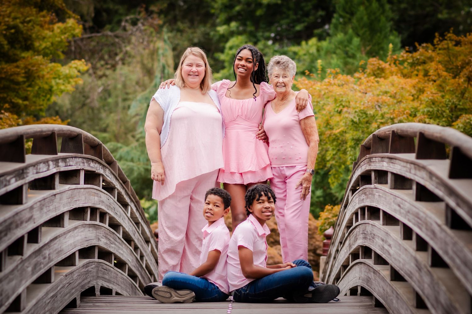 Group photo on curved wooden bridge surrounded by autumn foliage.