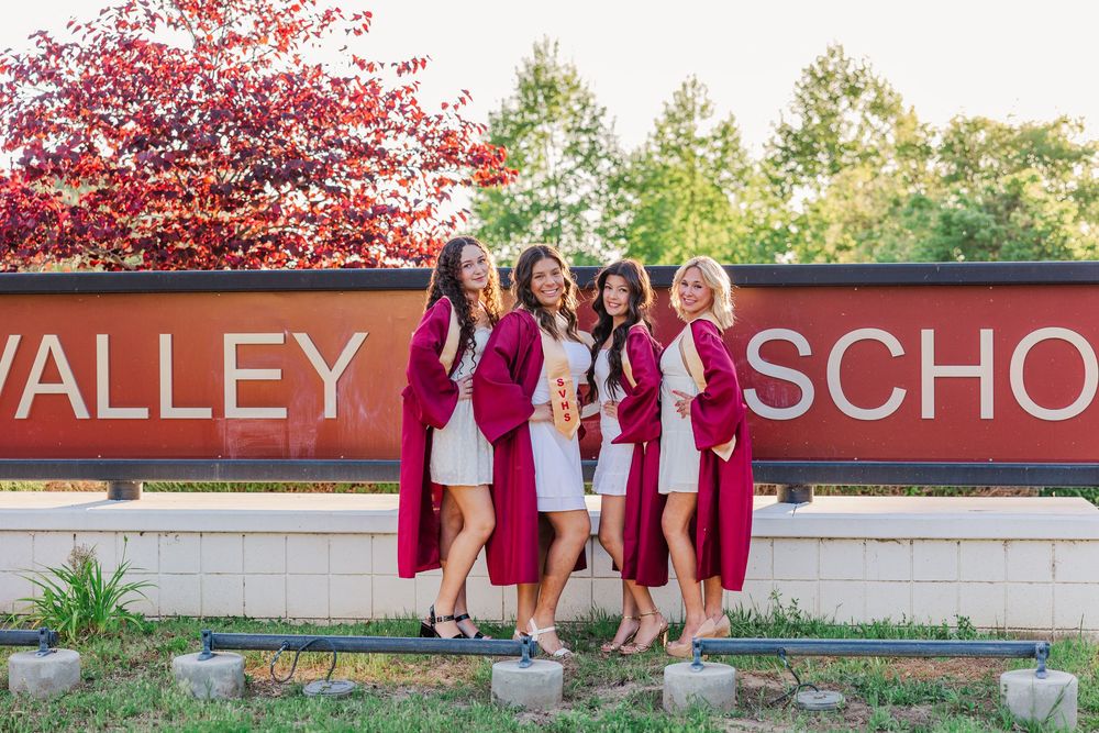 Friends gather at Simi Valley School entrance wearing coordinated burgundy outfits.Group poses by Simi Valley High School sign with pink flo