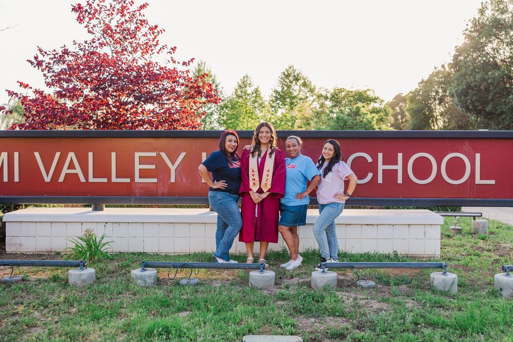Group poses by Simi Valley High School sign with pink flowering tree in background. Graduation Photos