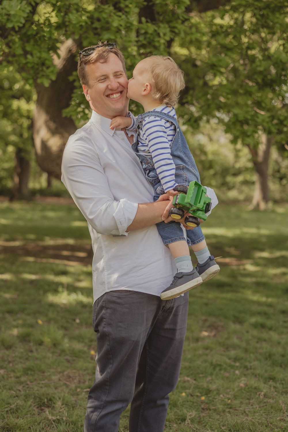 standing photo of boy and his dad cuddle on Wandsworth common