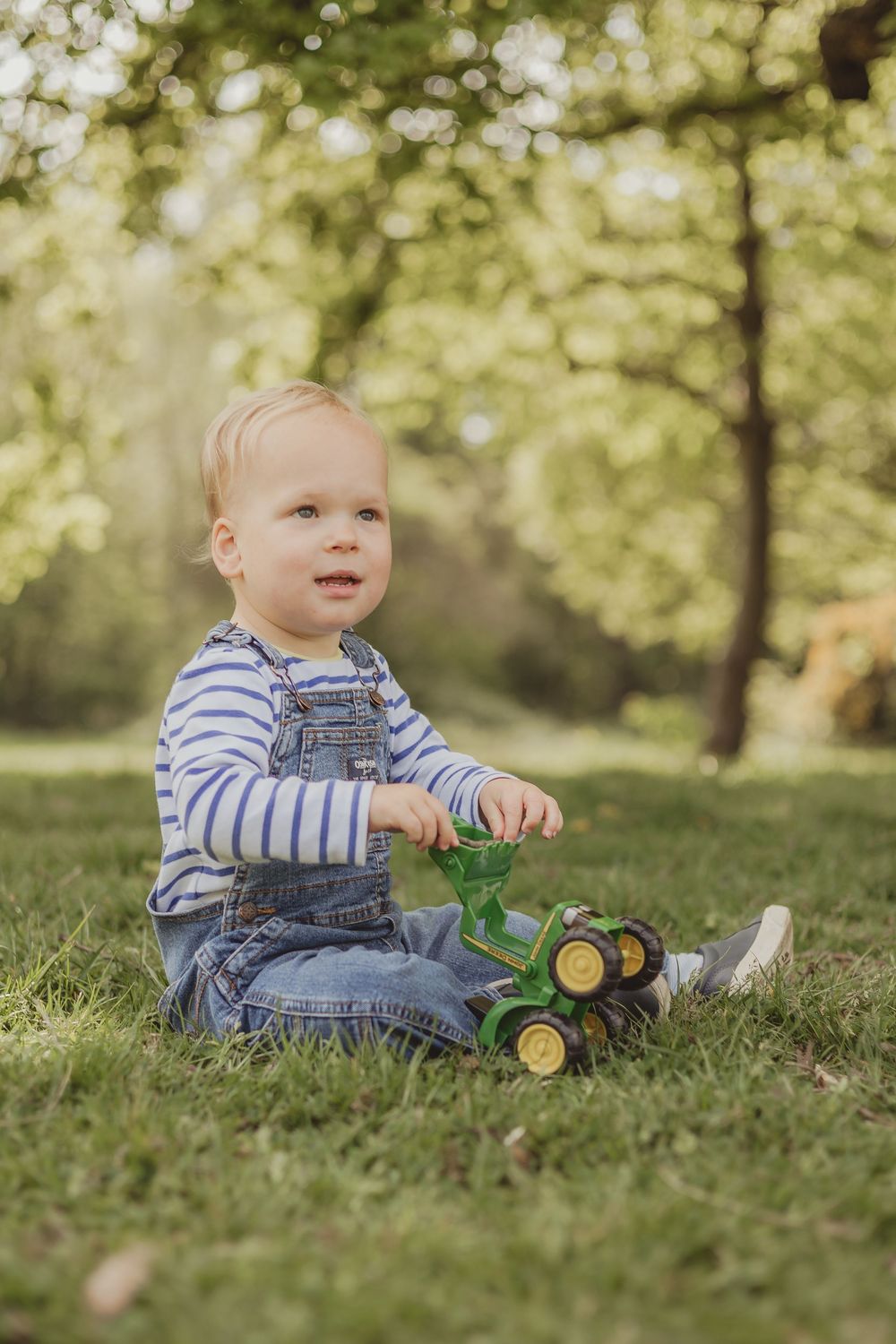 boy sits on the grass playing with tractor