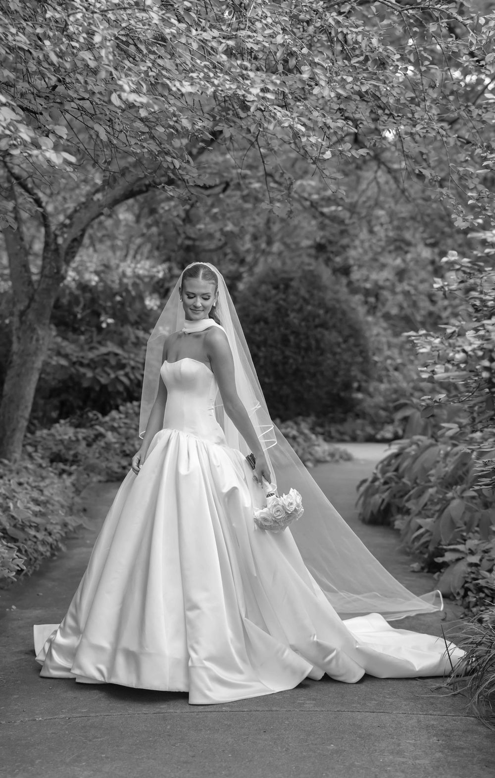 A bride in a classic white satin ballgown and cathedral veil poses gracefully in a garden setting across multiple frames.