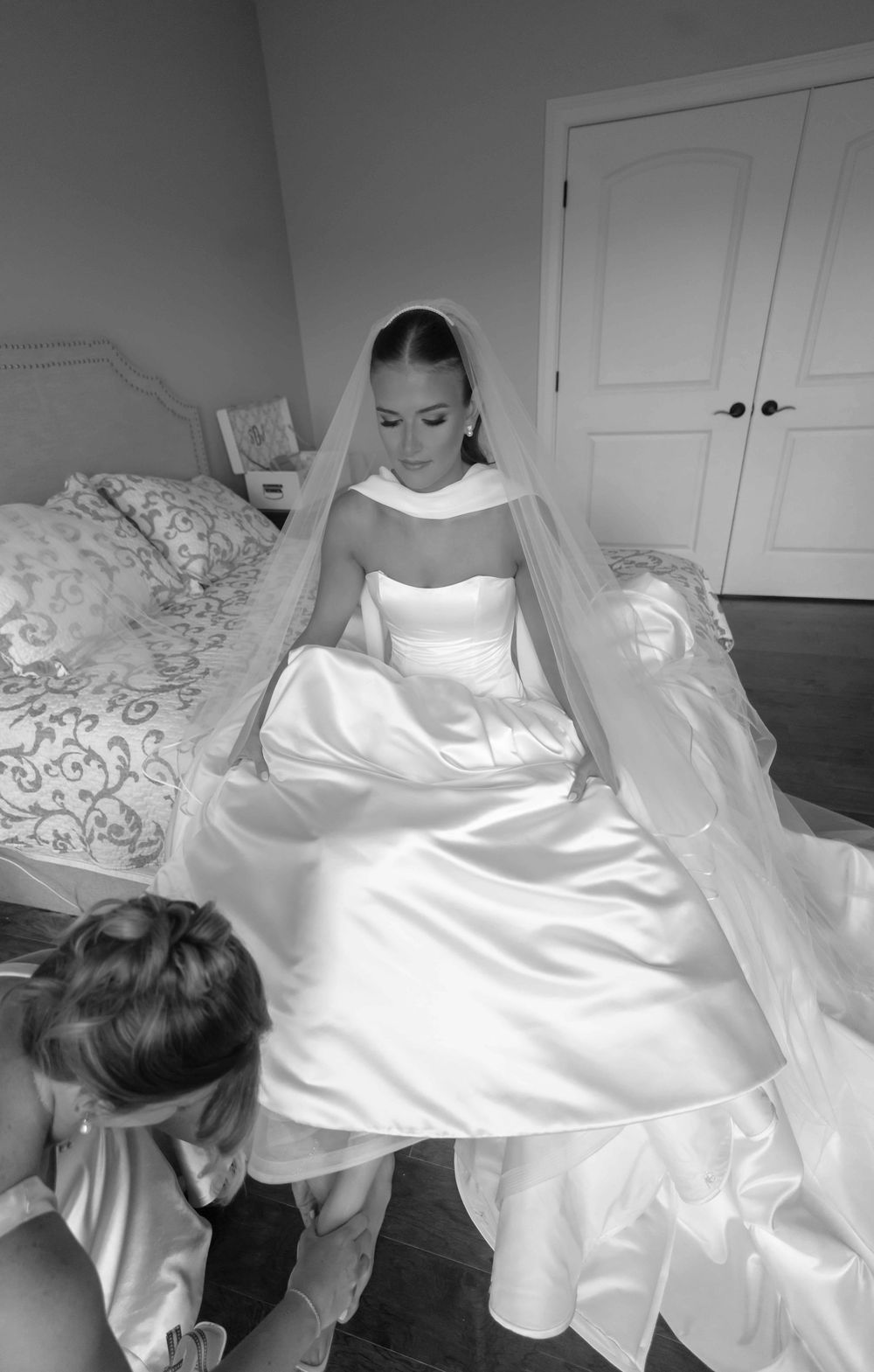 Black and white photo series showing a flowing white wedding dress being arranged and styled before a ceremony.