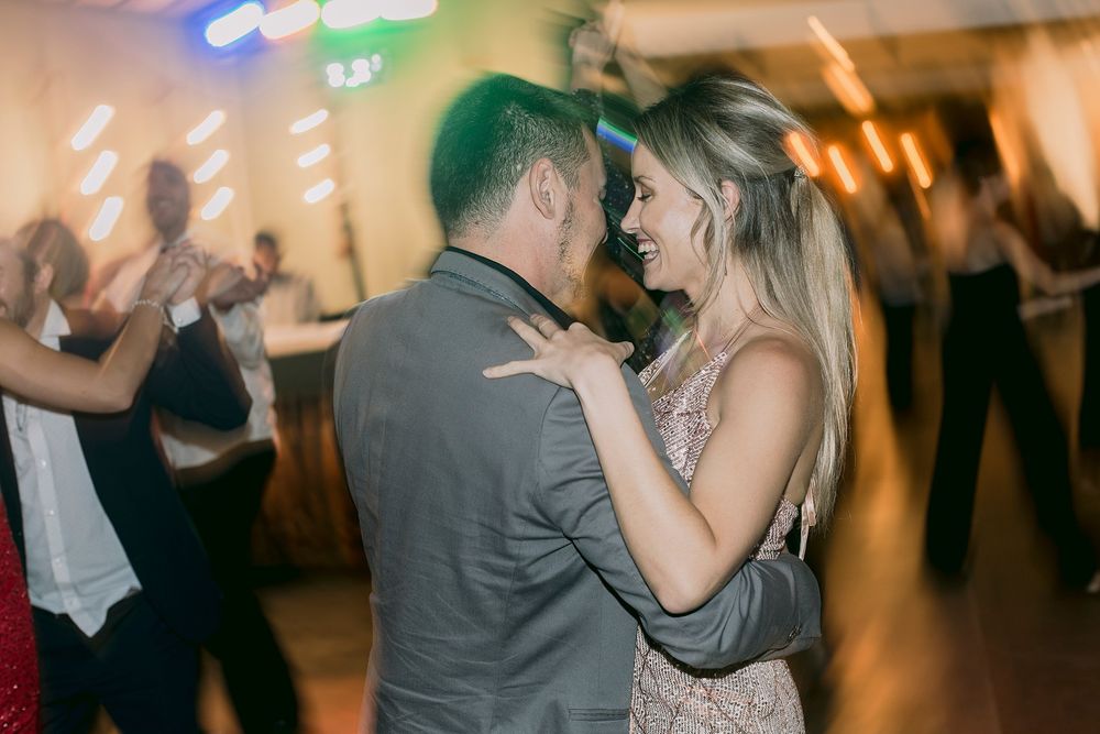 Couple sharing a romantic slow dance together at a warmly lit wedding reception.