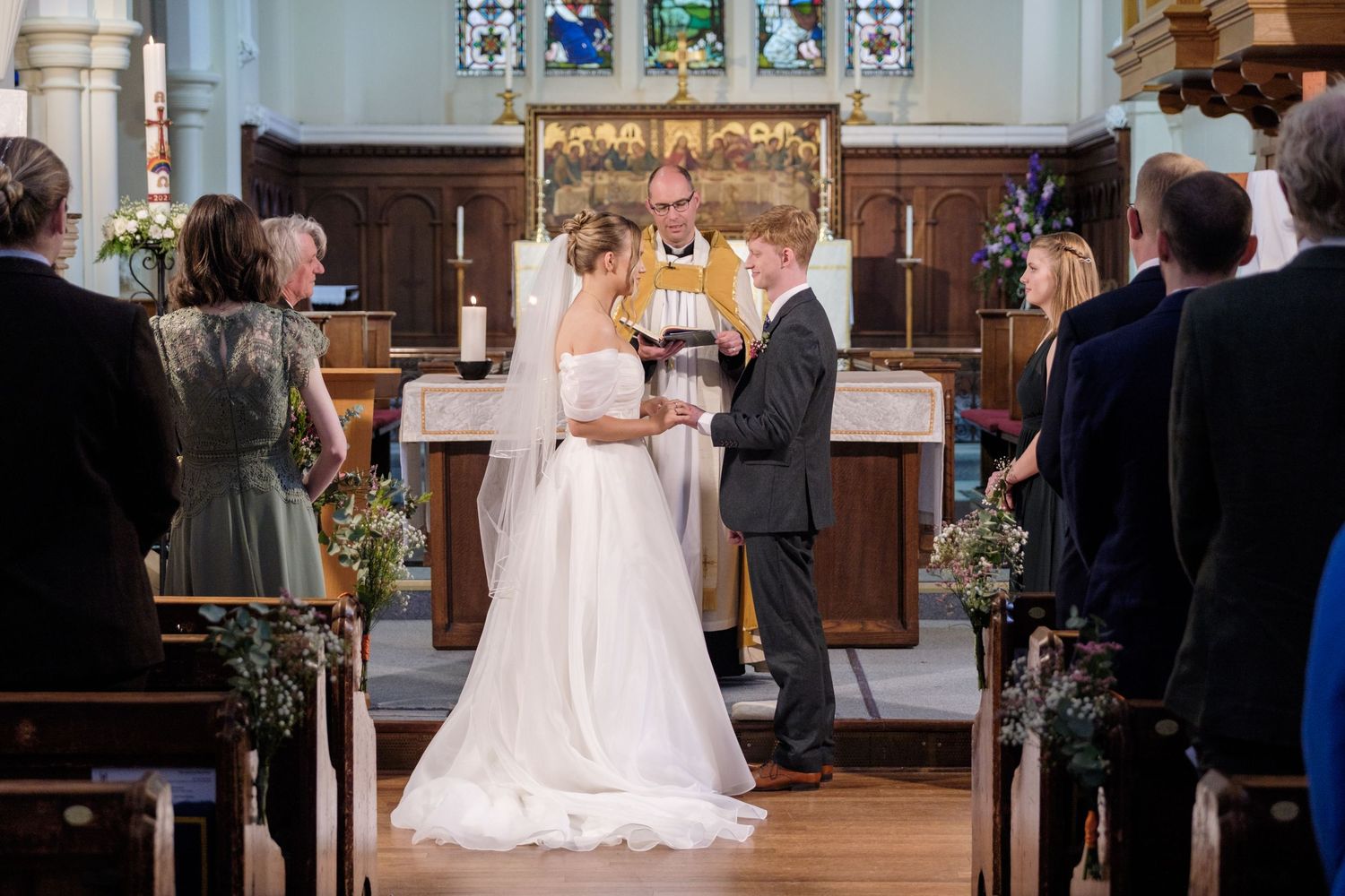 A romantic wedding ceremony takes place in a beautiful traditional church with ornate decorations and gathered guests.