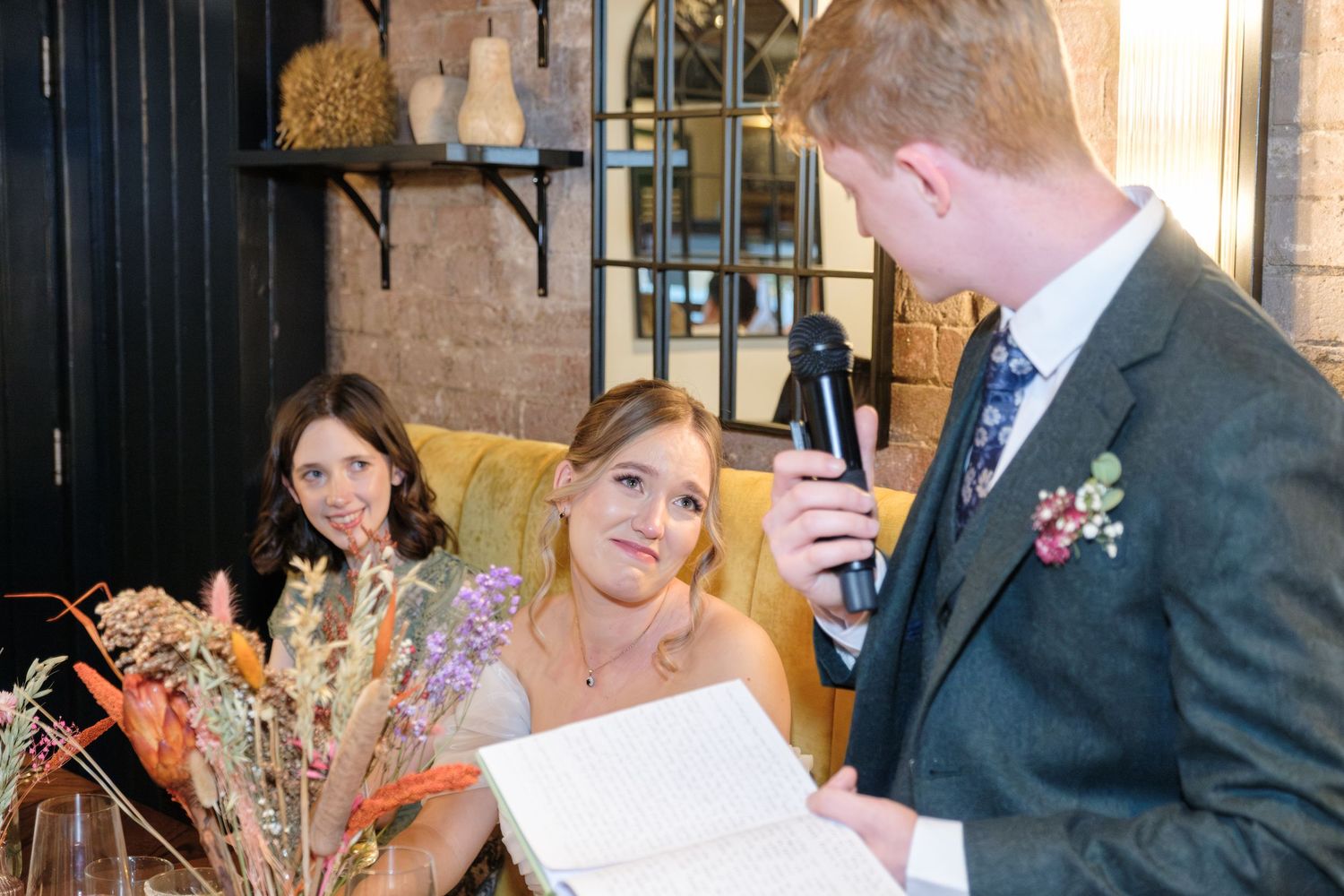 A couple shares a celebratory moment during a wedding ceremony with dried floral decorations in the background.