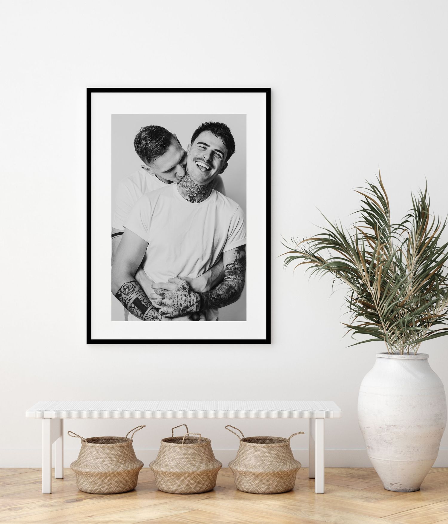 Black and white framed portrait displayed in a modern interior with woven baskets and a palm plant in a white vase.