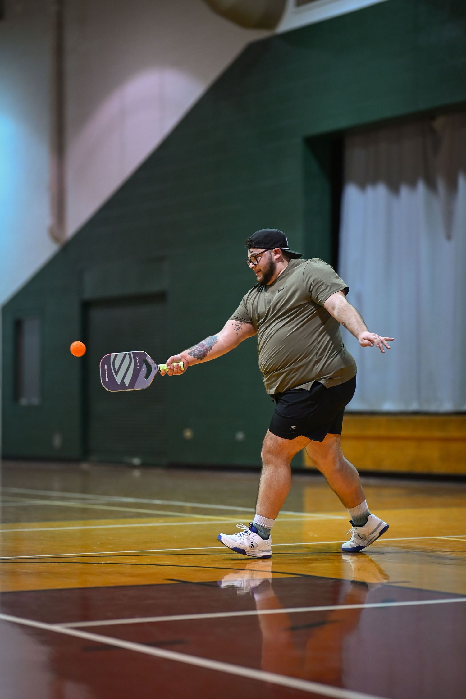 Myles (also known as @pickleballgay on Instagram) returns a volley in a game of pickleball at a local gym in Chicago