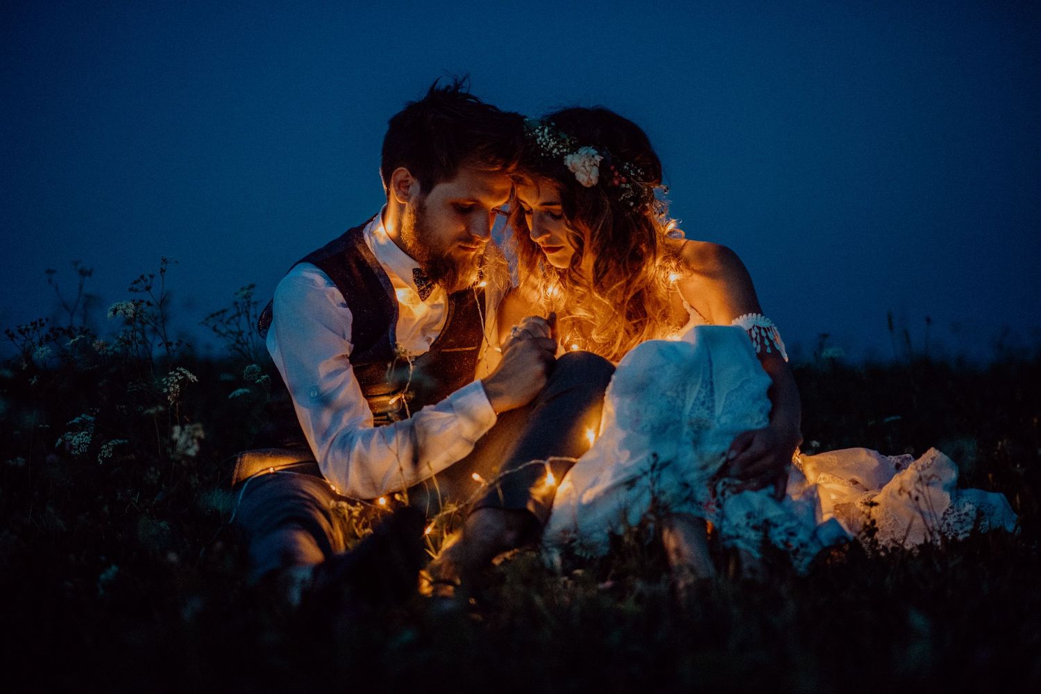 Romantic wedding photo showing intimate moment between a couple in formal attire with pearl dress strap and white tuxedo.