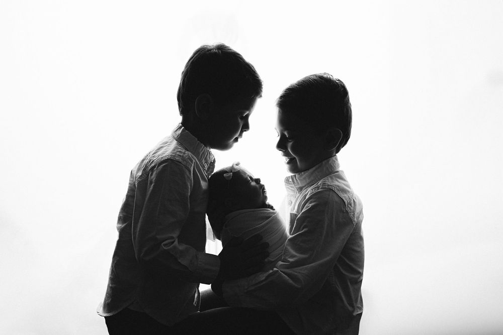 Black and white silhouettes of two people in an intimate pose against a light background. – newborn photographer Paloma Schell Houston TX