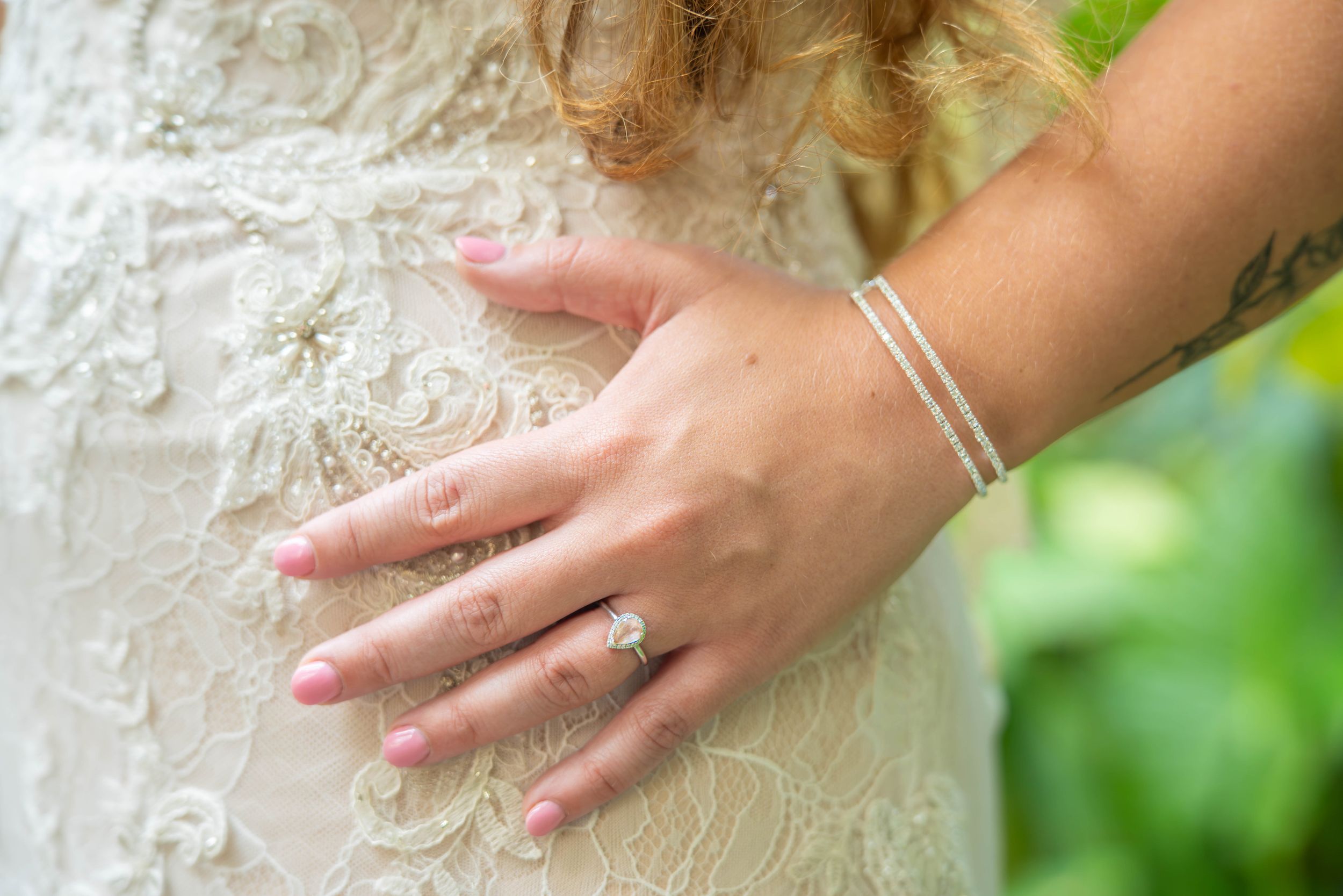 Close-up shots of hands displaying an engagement ring against a blurred green natural background.